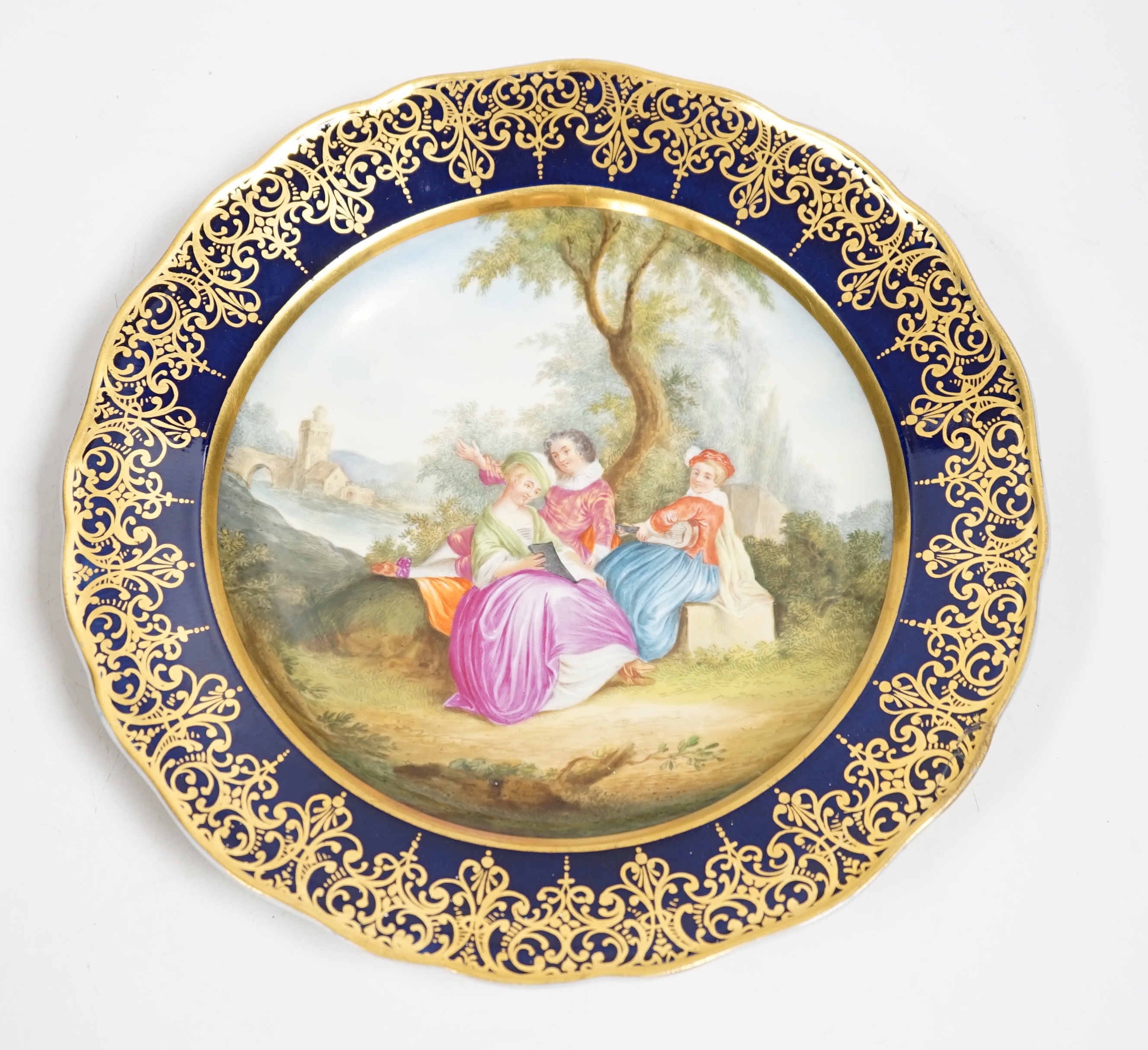 A Meissen-style rich blue and gilt bordered dish, the centre painted with a romantic scene with figures